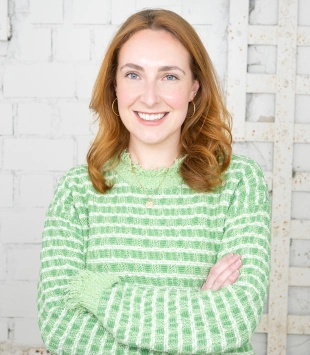 Hannah Sollé, Teamlead Influencer Marketing, hi!share.that, with a green pullover in front of a white brick wall